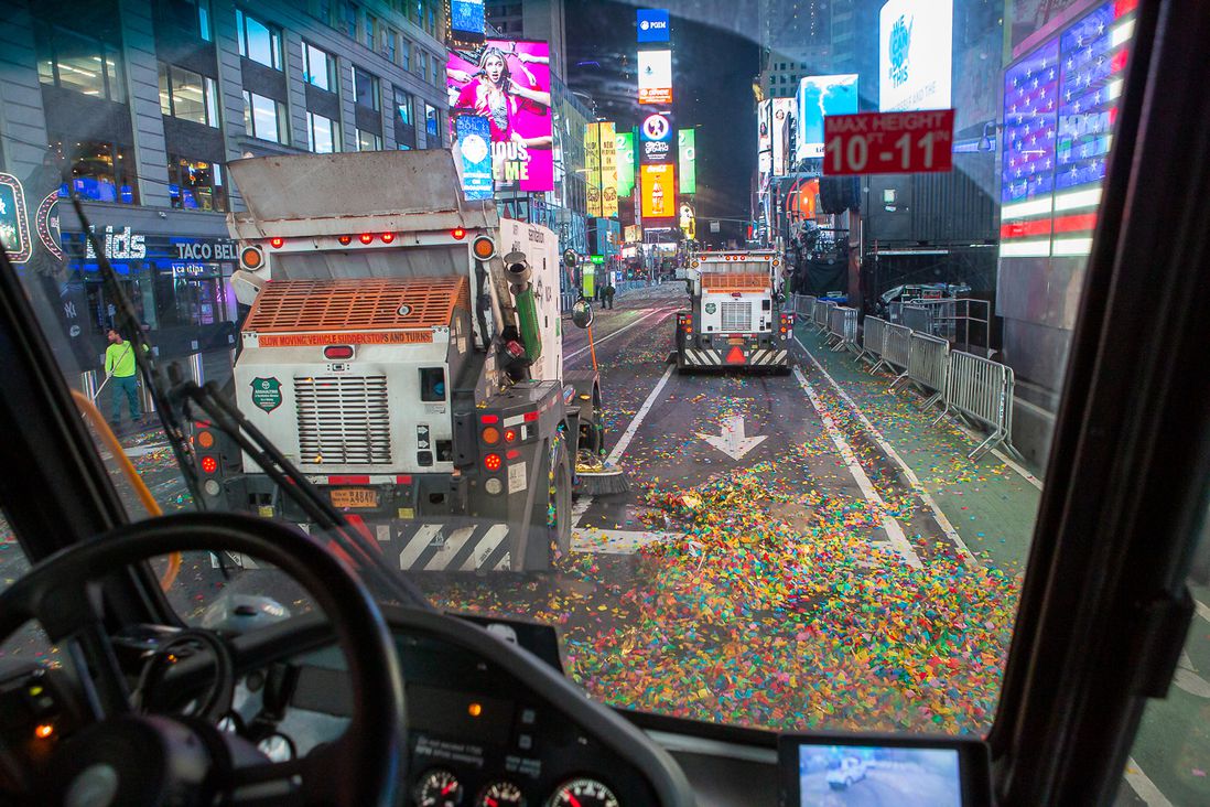 The Department of Sanitation crews cleaning up Times Square after revelers ring in 2022 - workers aided by mechanical sweepers, big collection trucks, and regular brooms.